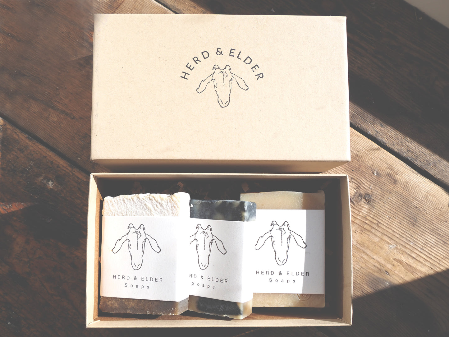Goat milk soap gift set in eco-friendly Kraft box featuring three artisan soap bars with Herd & Elder branding.