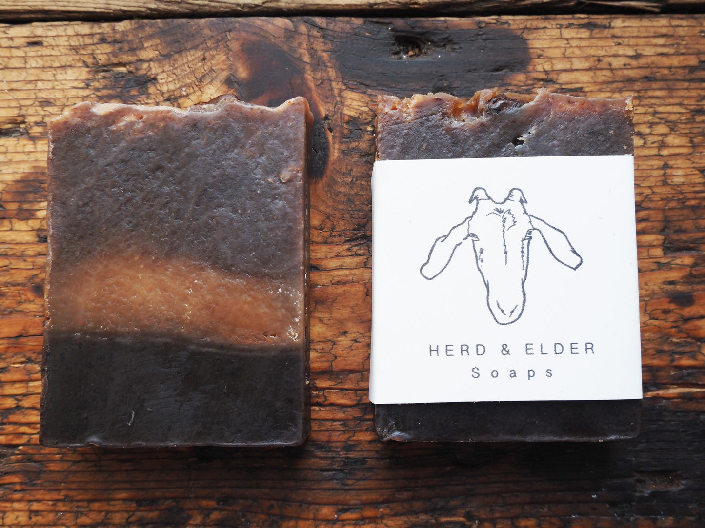 Goats Milk Soap bar featuring a rich blend of coffee and vanilla, labeled as Herd & Elder Soaps on wooden background.
