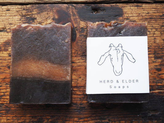 Goats Milk Soap bar featuring a rich blend of coffee and vanilla, labeled as Herd & Elder Soaps on wooden background.