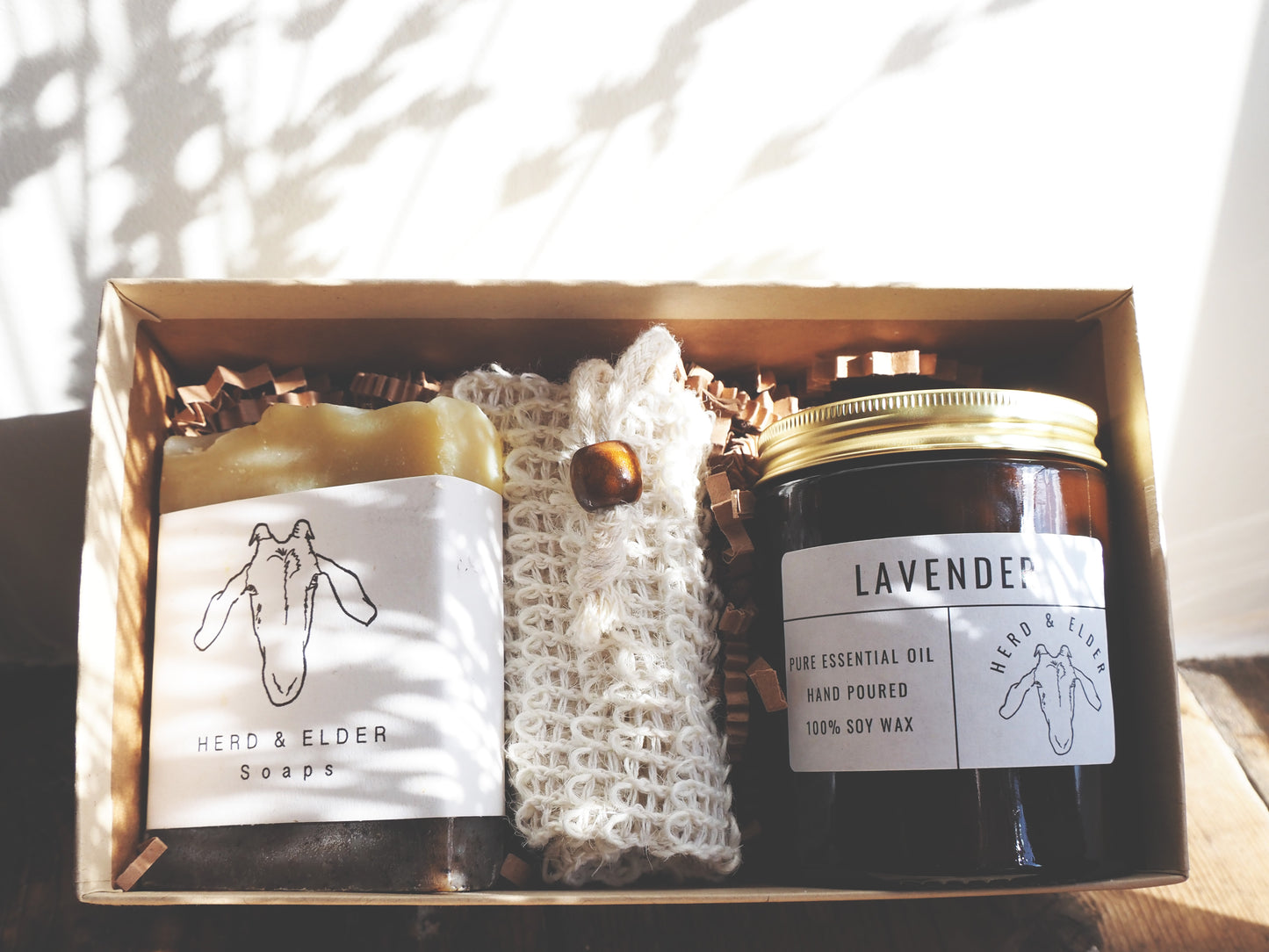 Gift set featuring handcrafted goat milk soap and lavender essential oil candle in eco-friendly packaging.