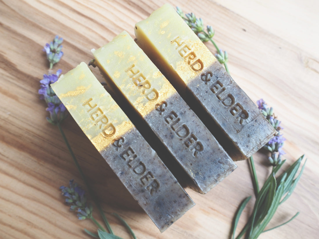 What Makes Our Goat Milk Soap Different - bars of soap with natural herbs and flowers on wooden surface.