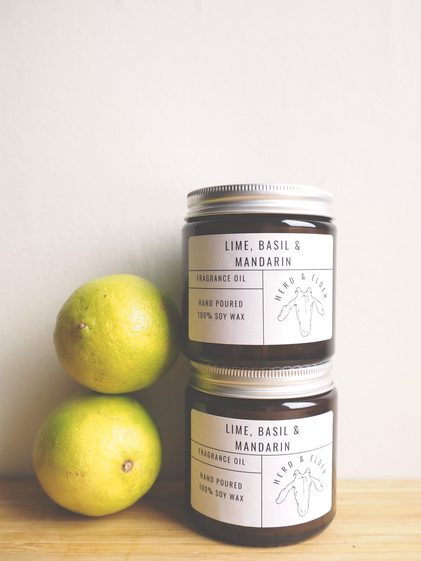 Lime Basil and Mandarin Soy Wax Candle jars beside fresh limes, showcasing the refreshing fragrance.