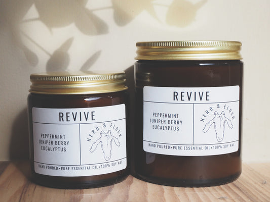 Revive - Essential Oil Eucalyptus, Peppermint & Juniper Berry Candle in amber jars on a wooden surface.