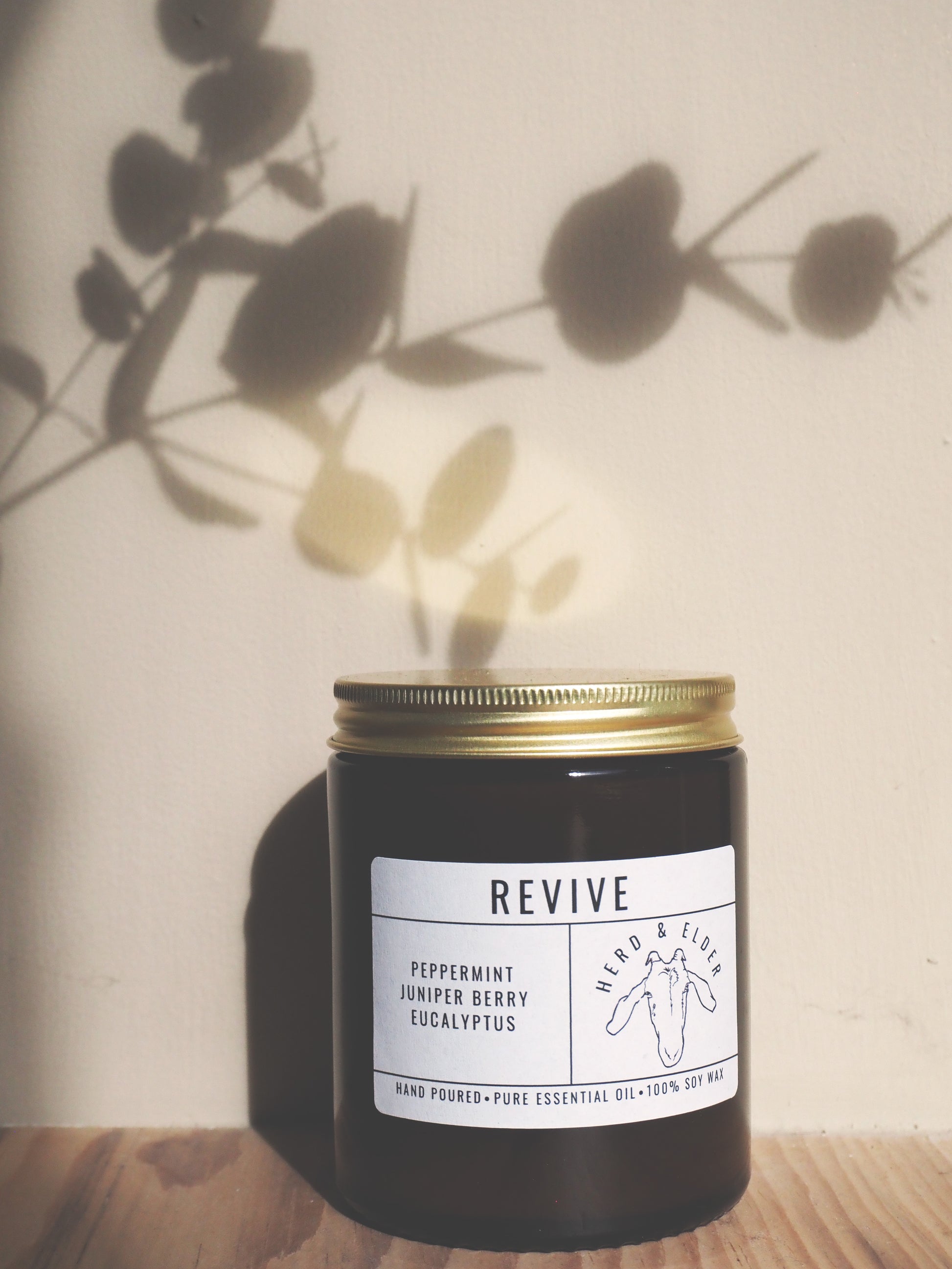 Revive - Essential Oil Eucalyptus, Peppermint & Juniper Berry Candle displayed in a dark jar with a gold lid.