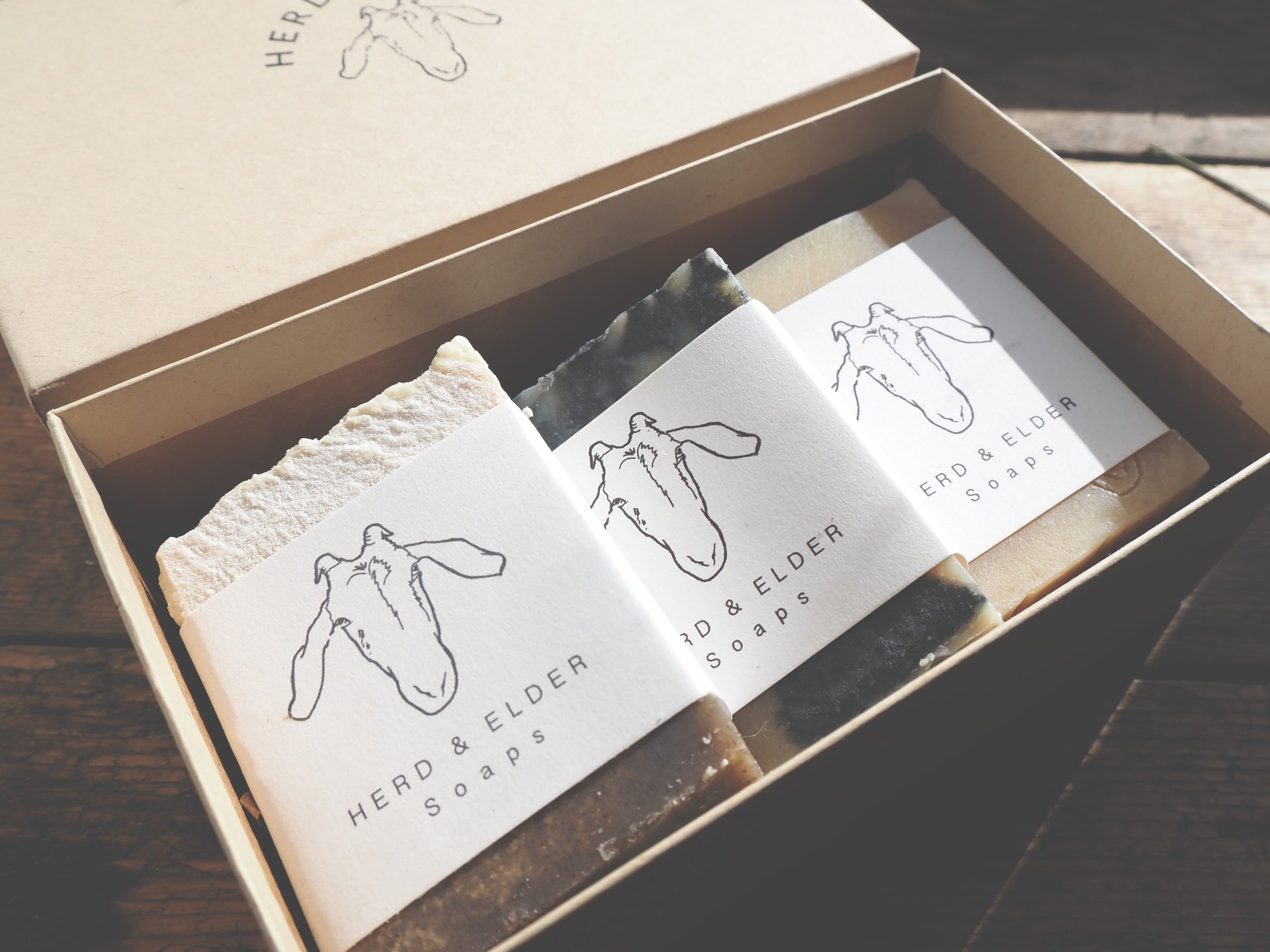Goat Milk Soap Gift Set in an eco-friendly box featuring three artisan soaps with branding labels.