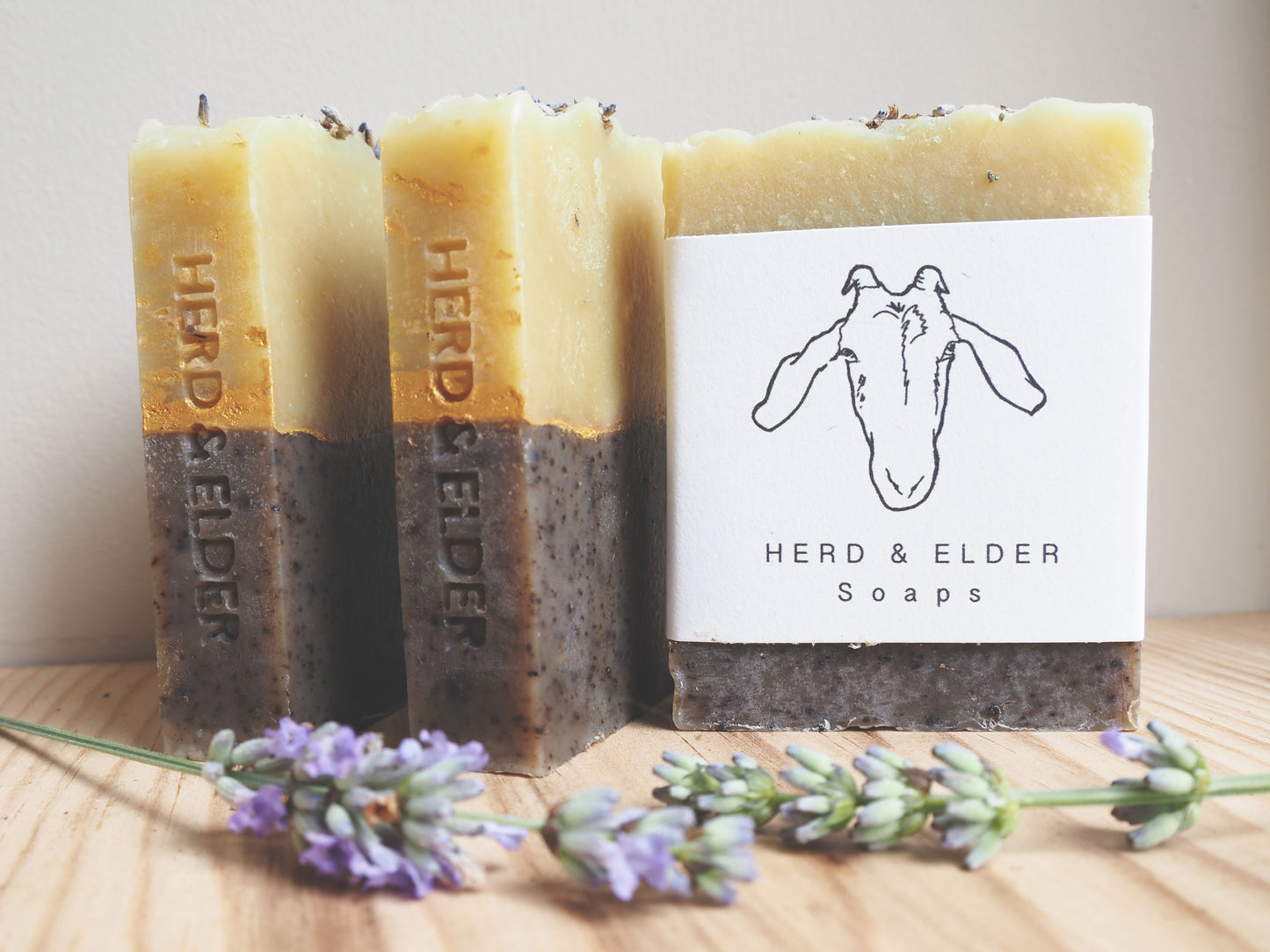 Three bars of goats milk soap with lavender, handcrafted by Herd & Elder, showcasing natural ingredients and rustic design.